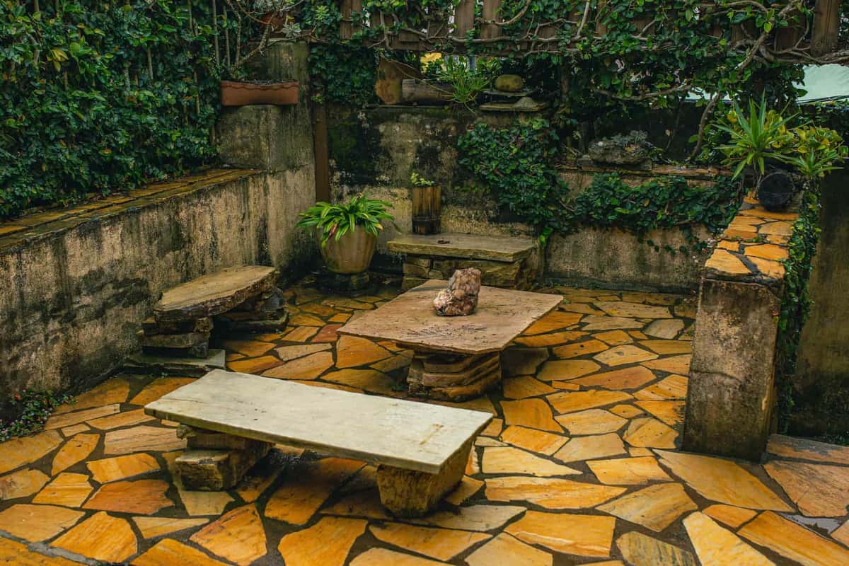A stone patio with seating in a backyard
