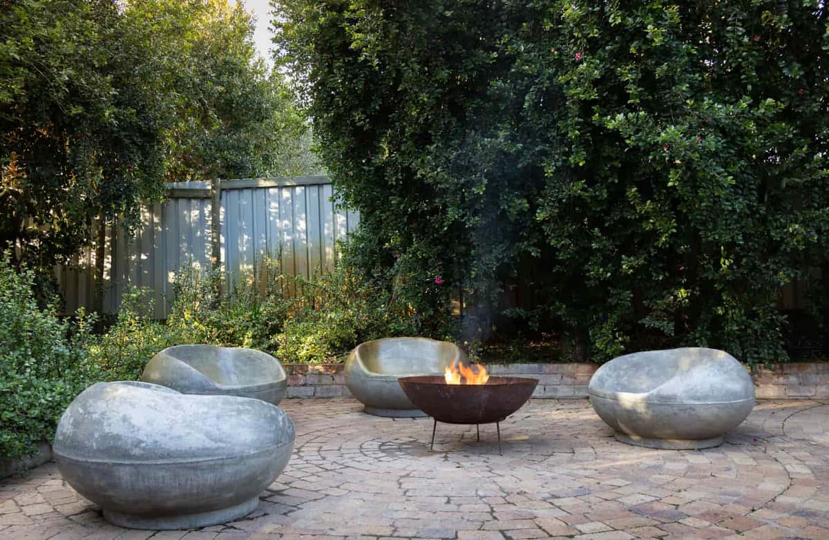 A steel fire pit on a stone patio at dusk